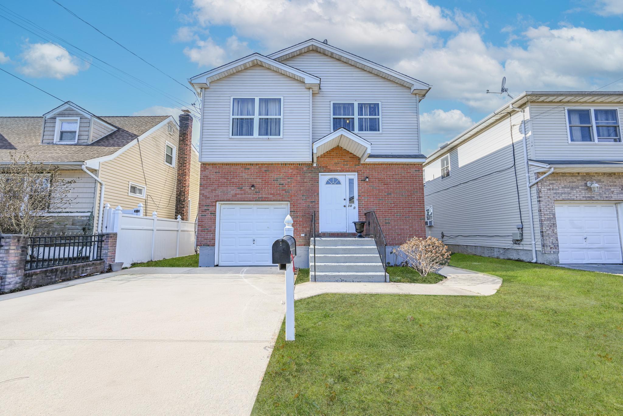 View of front facade featuring a garage and a front lawn