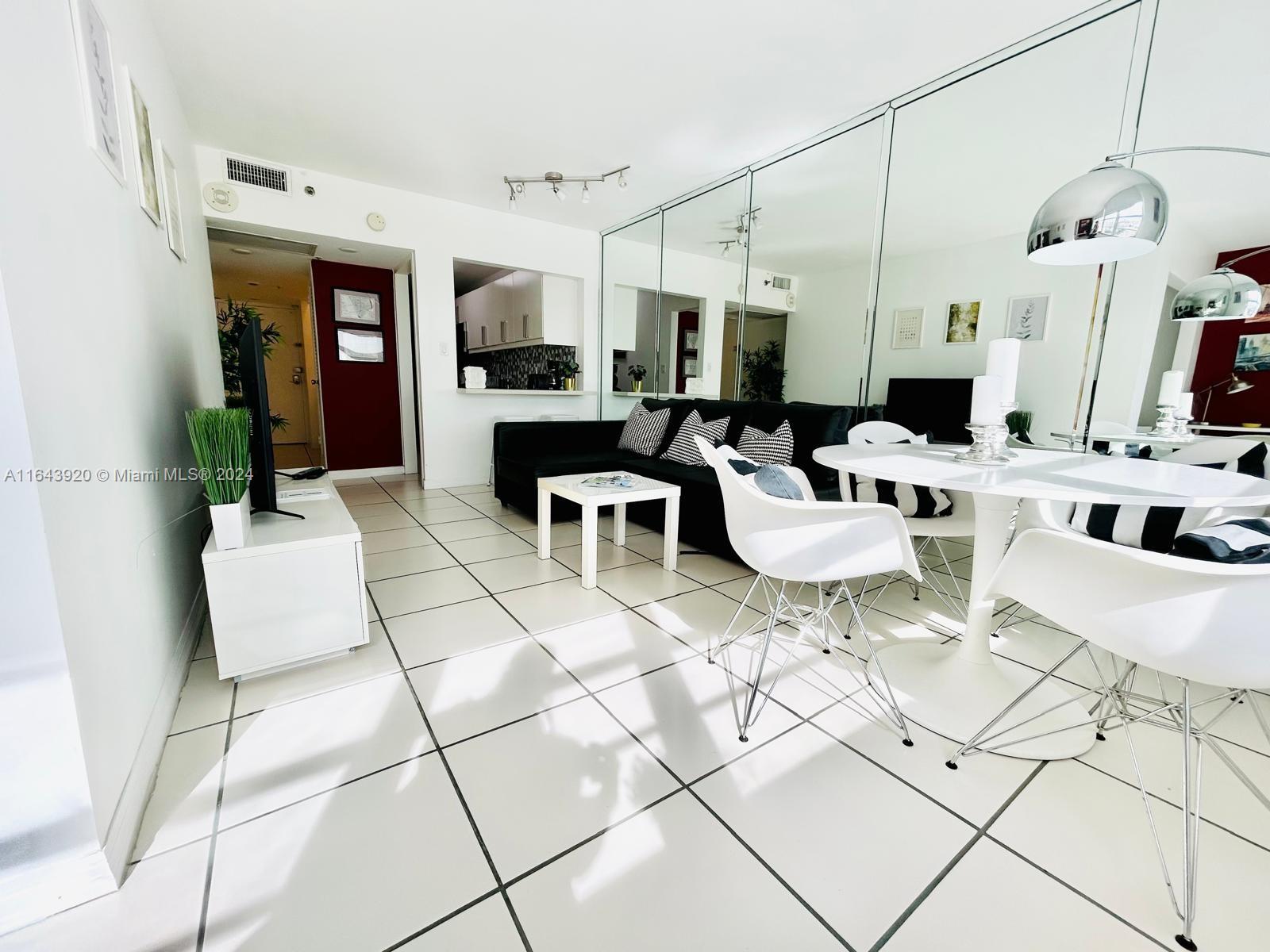 a living room with lots of white furniture and a dining table