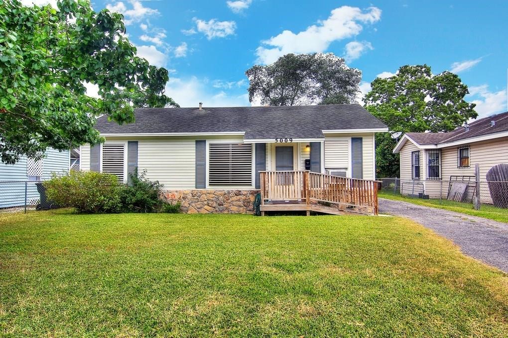 a view of a house with a yard and a large tree