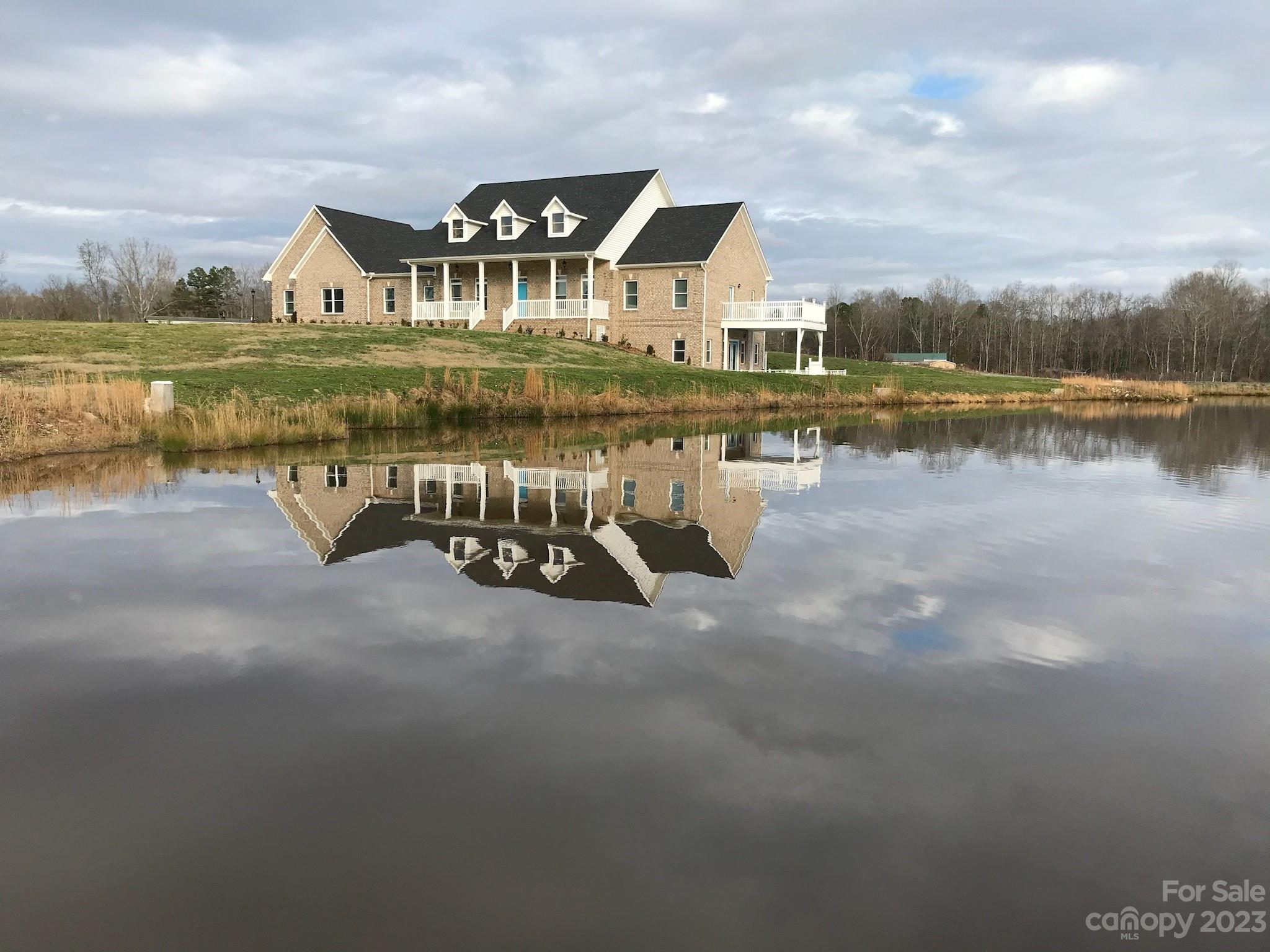 a view of a lake with a house and a yard with swimming pool