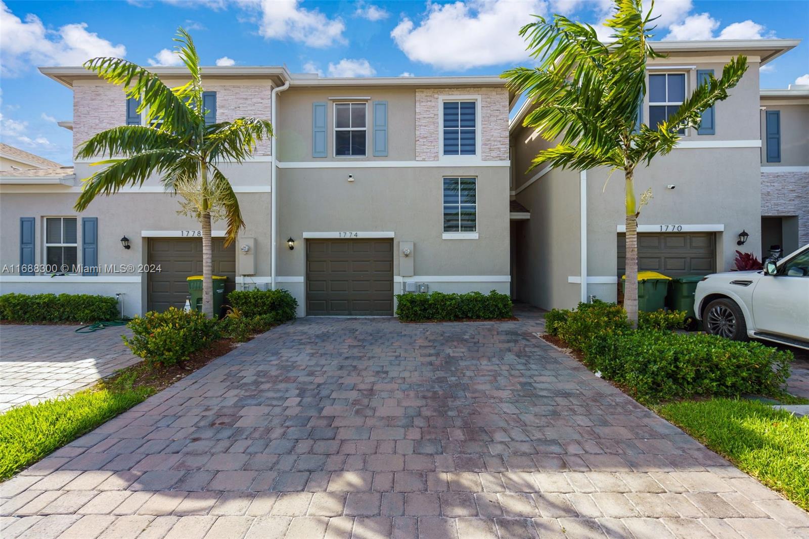 a palm tree sitting in front of a house with potted plants