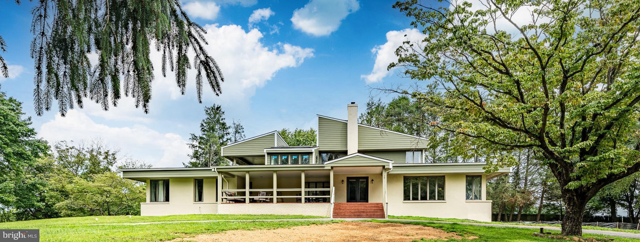 a view of a white house with a big yard and large trees