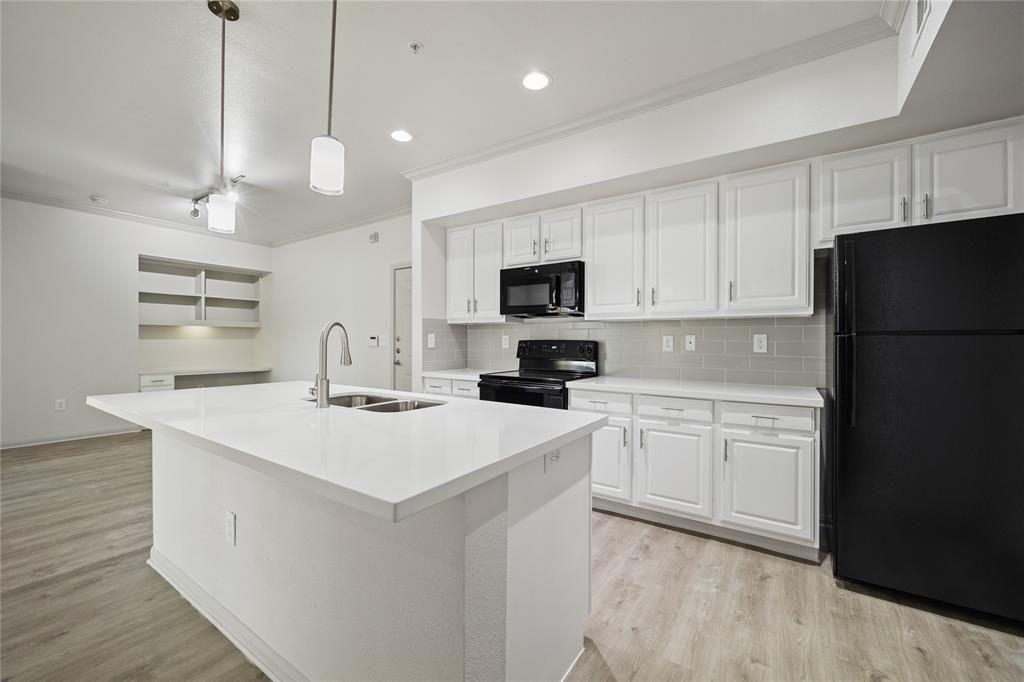 a kitchen with kitchen island a white counter top space stainless steel appliances and cabinets