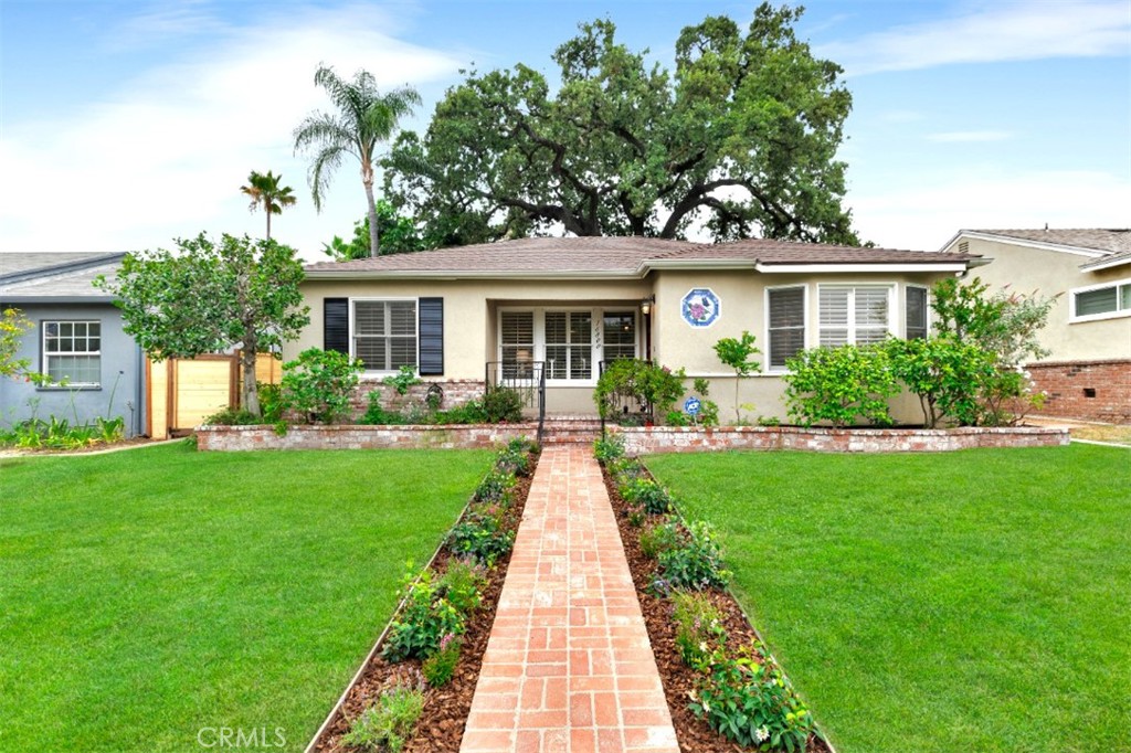 a front view of a house with a yard and potted plants