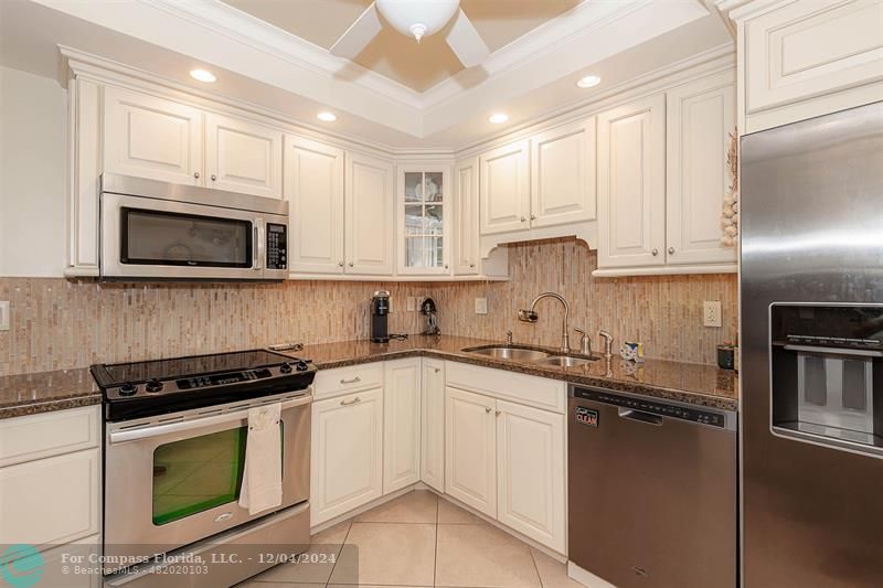 a kitchen with granite countertop white cabinets stainless steel appliances and sink