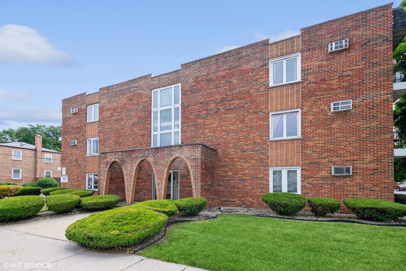 a brick building with a yard and a large parking space