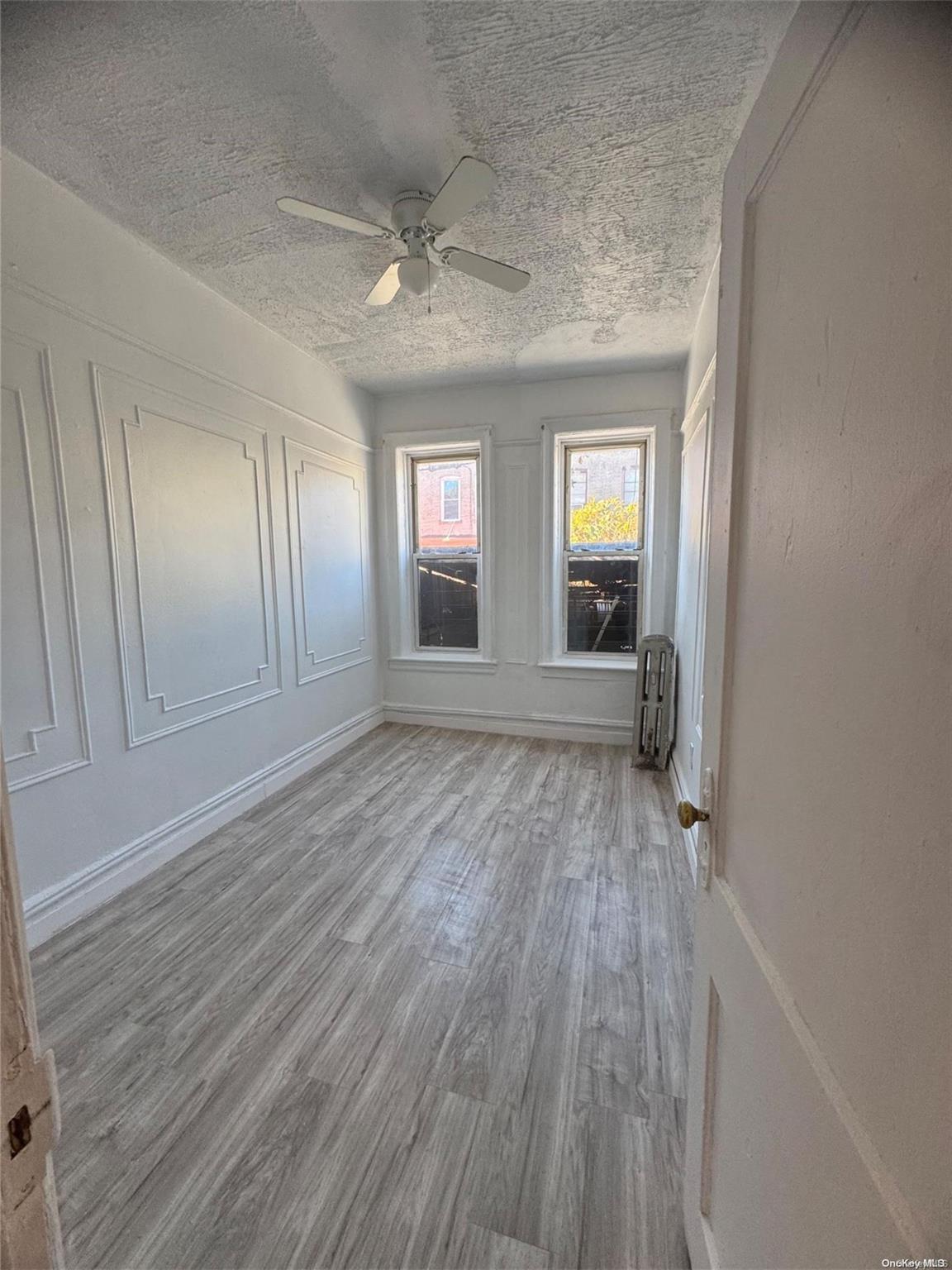 a view of an empty room with wooden floor and window