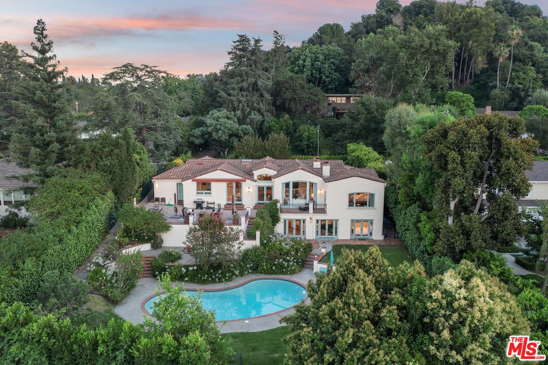 an aerial view of a house with yard and trees in the background