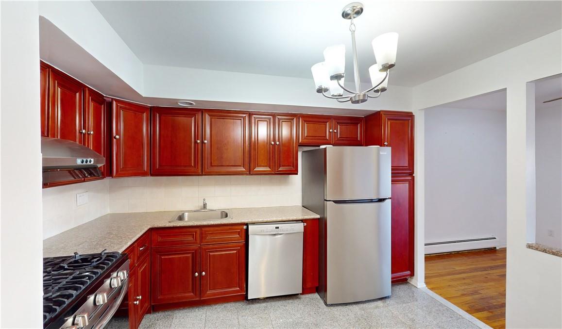 Kitchen featuring a baseboard heating unit, light hardwood / wood-style flooring, stainless steel appliances, sink, and pendant lighting