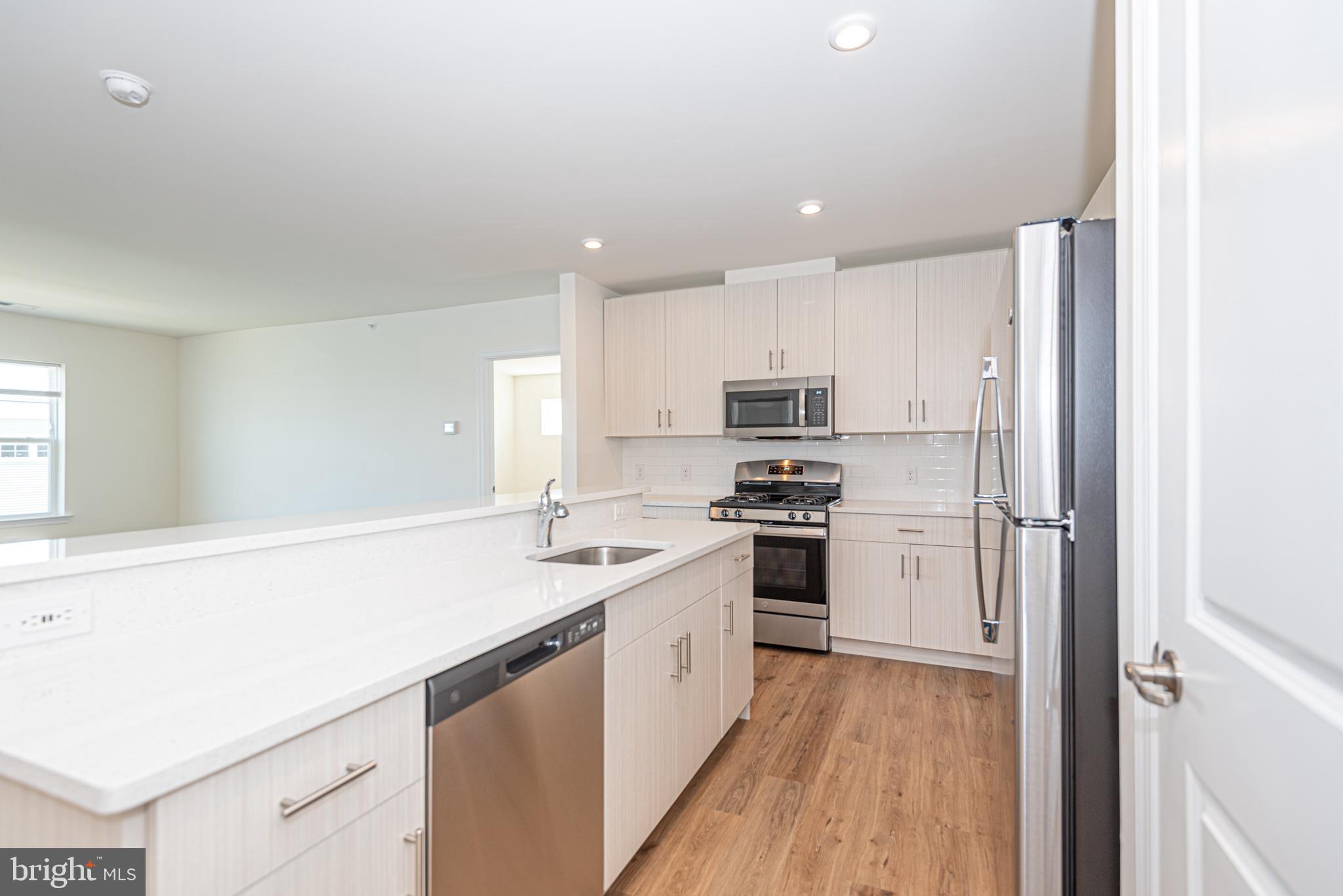 a kitchen with stainless steel appliances a sink a stove a refrigerator and cabinets