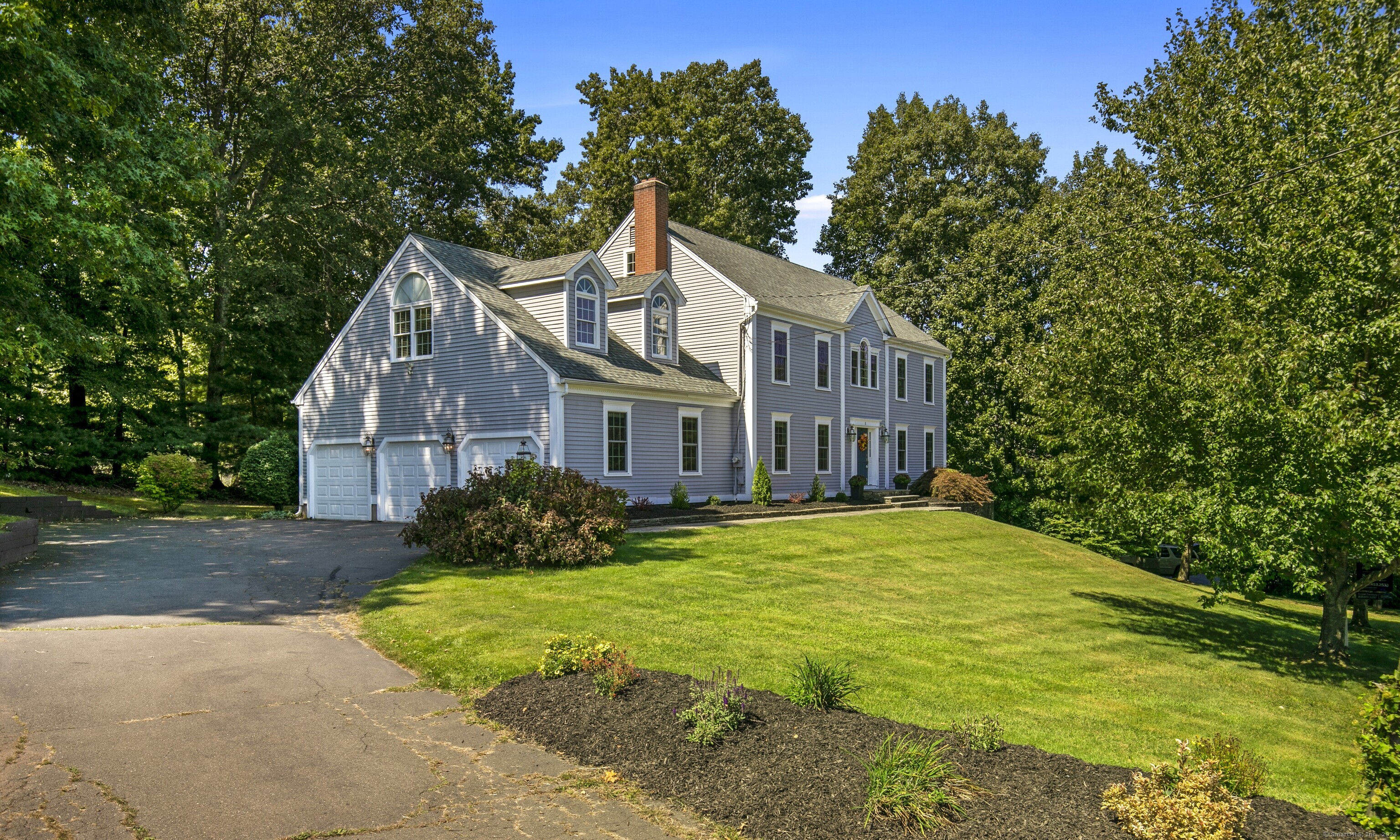 a view of a big house with a big yard plants and large trees