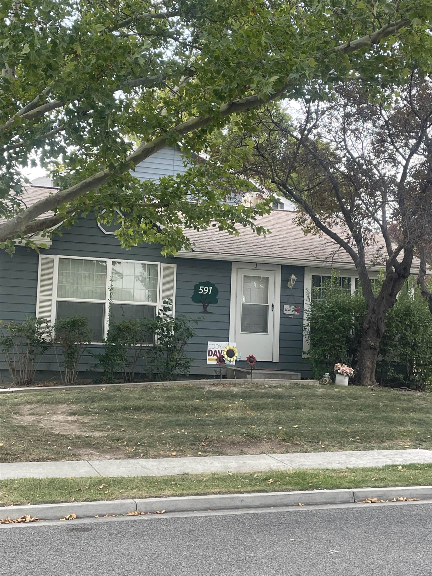 a front view of a house with a garden and trees