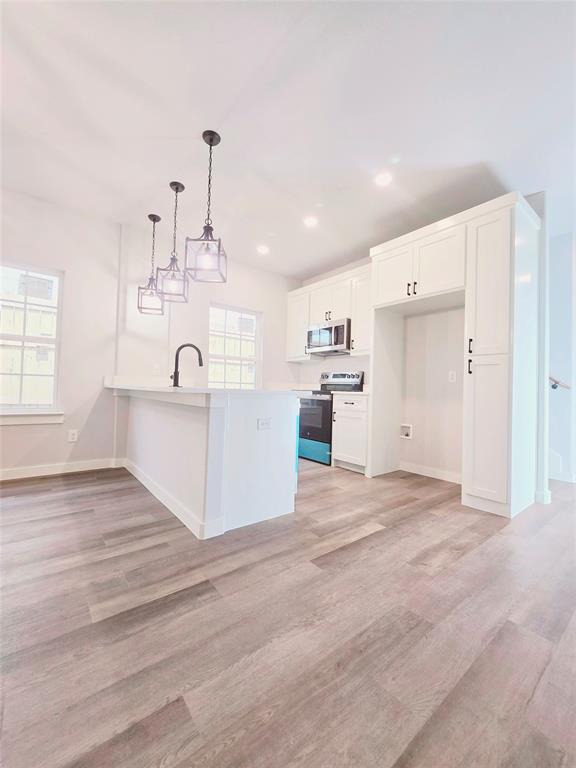 a view of a kitchen with a sink and dishwasher a refrigerator with white cabinets