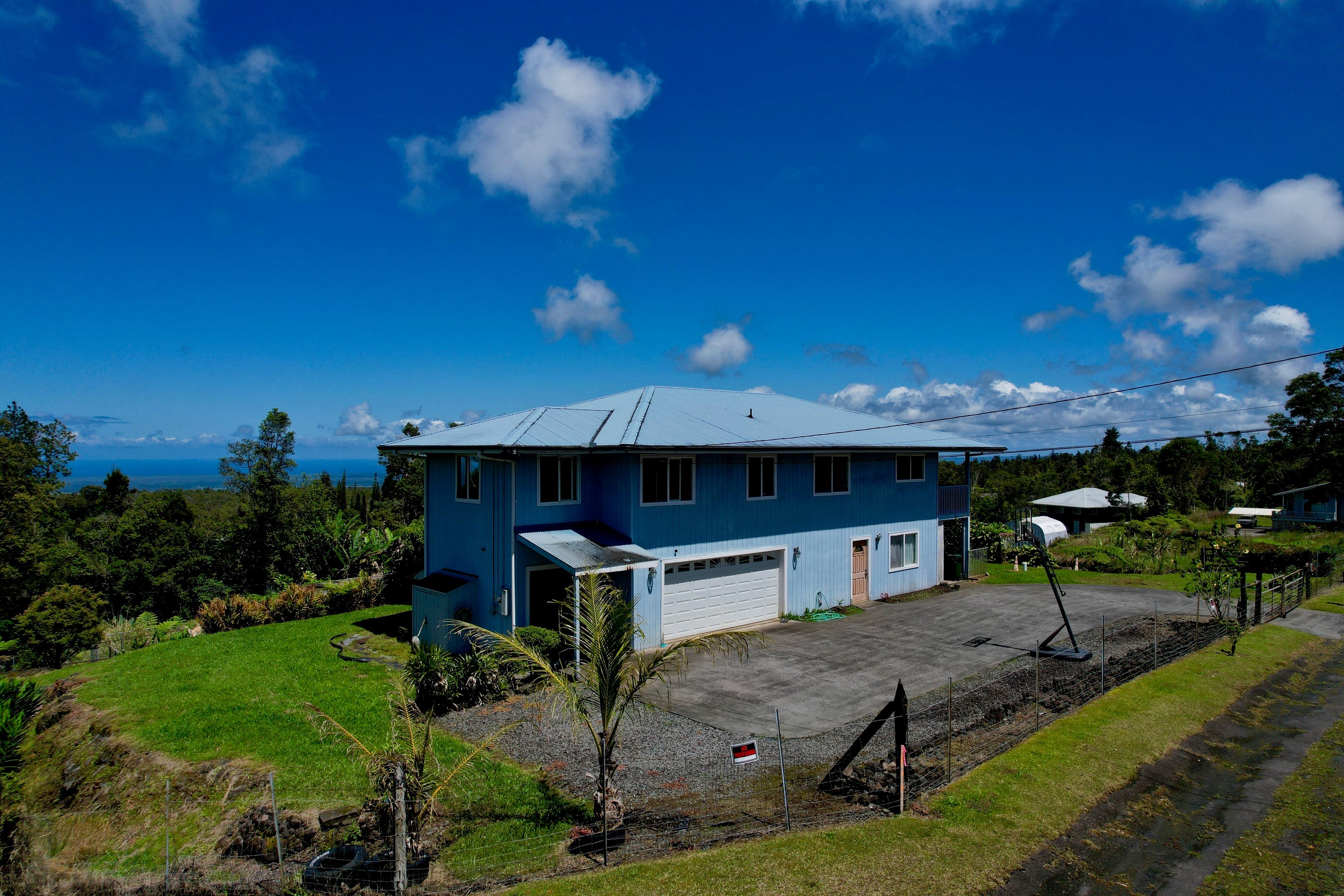 Front view of house with entry gate and cement driveway.