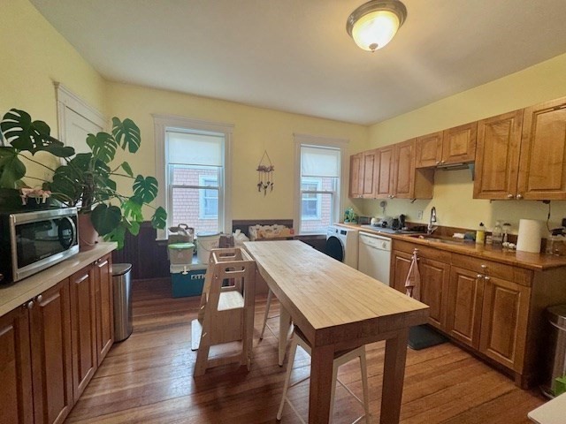 a kitchen with granite countertop a stove a sink dishwasher and a refrigerator with wooden floor