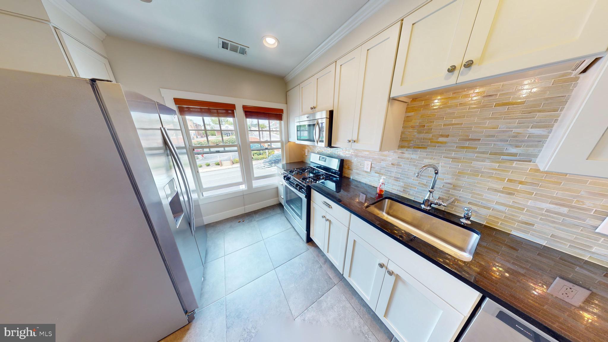 a view of a large kitchen with a sink and wooden floor