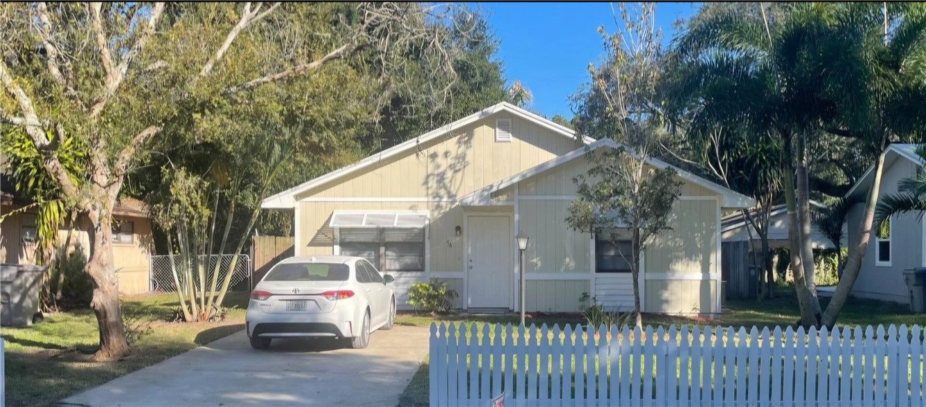 a view of a house with a small yard and large trees