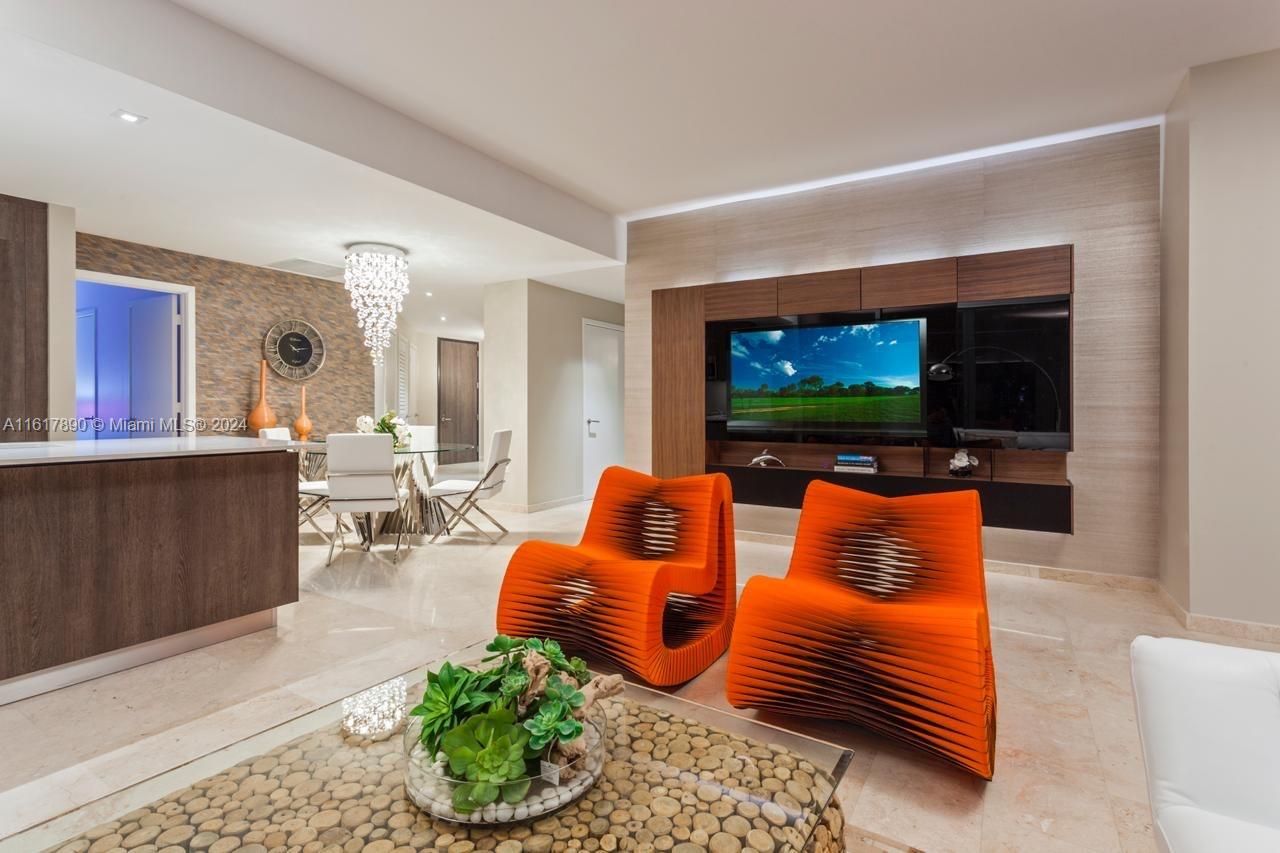 a living room with furniture a flat screen tv and a floor to ceiling window