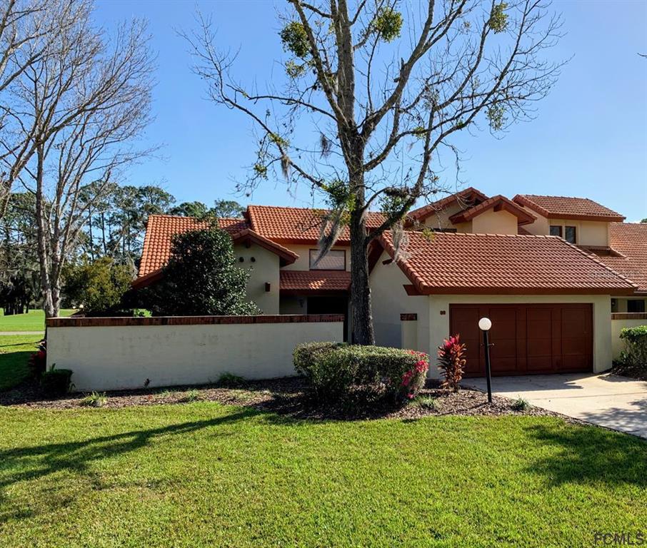 a view of a house with a yard and a large tree