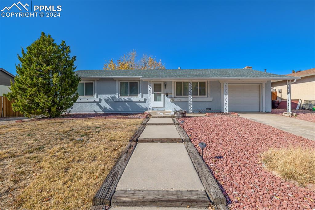 Ranch-style home featuring a front lawn, covered porch, and a garage