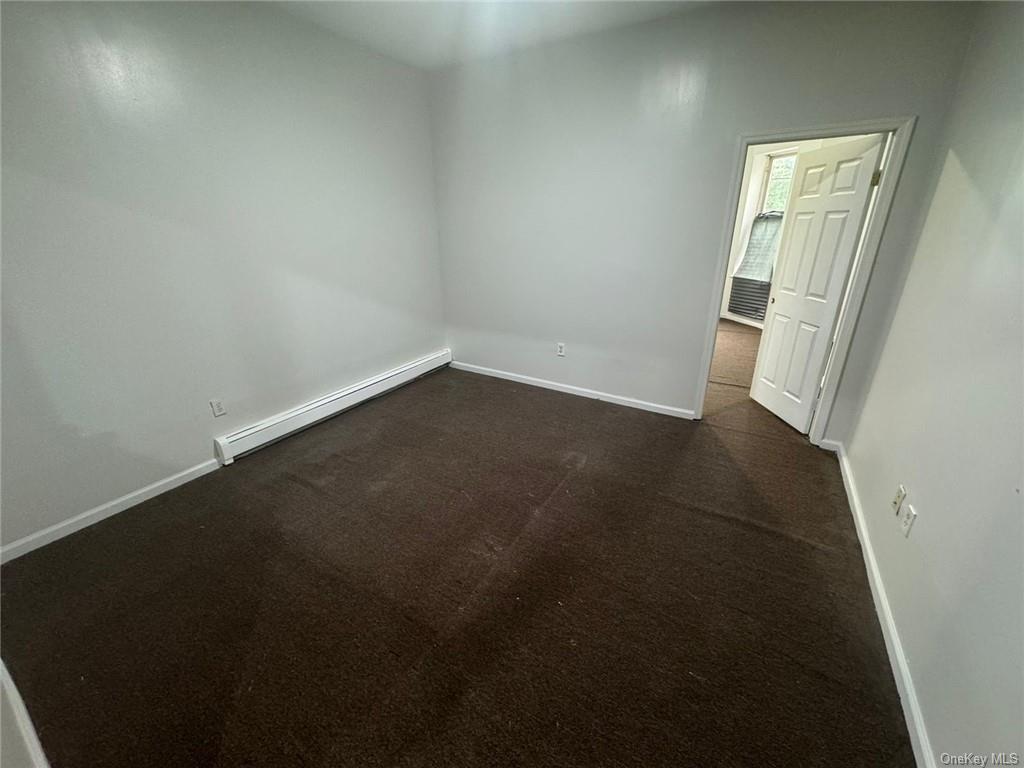 Living room with a baseboard heating unit and dark carpet