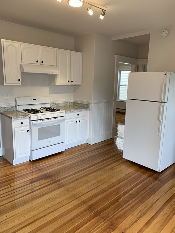 a kitchen with wooden floors and white appliances