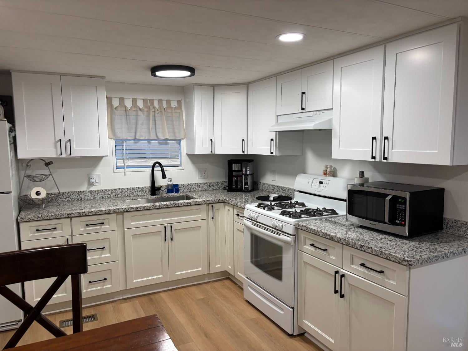 a kitchen with granite countertop white cabinets and white appliances