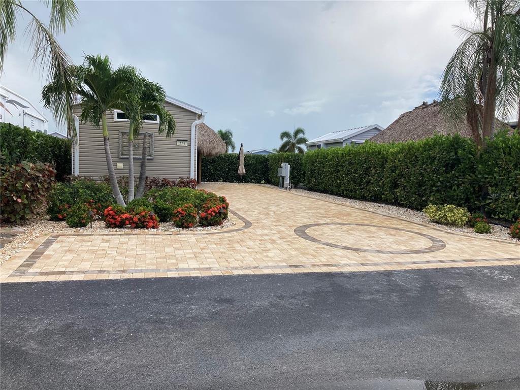 a white house with a yard plants and palm trees