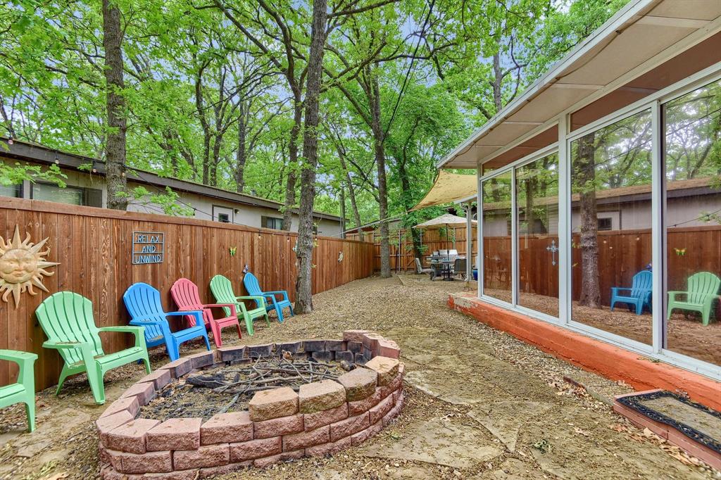 a view of a backyard with table and chairs potted plants and large tree