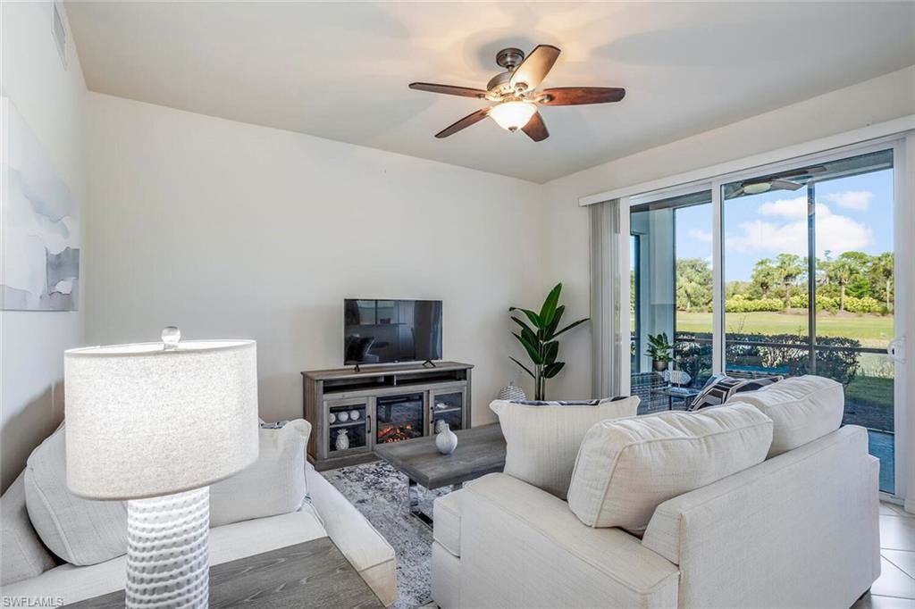 a living room with furniture a flat screen tv and a large window