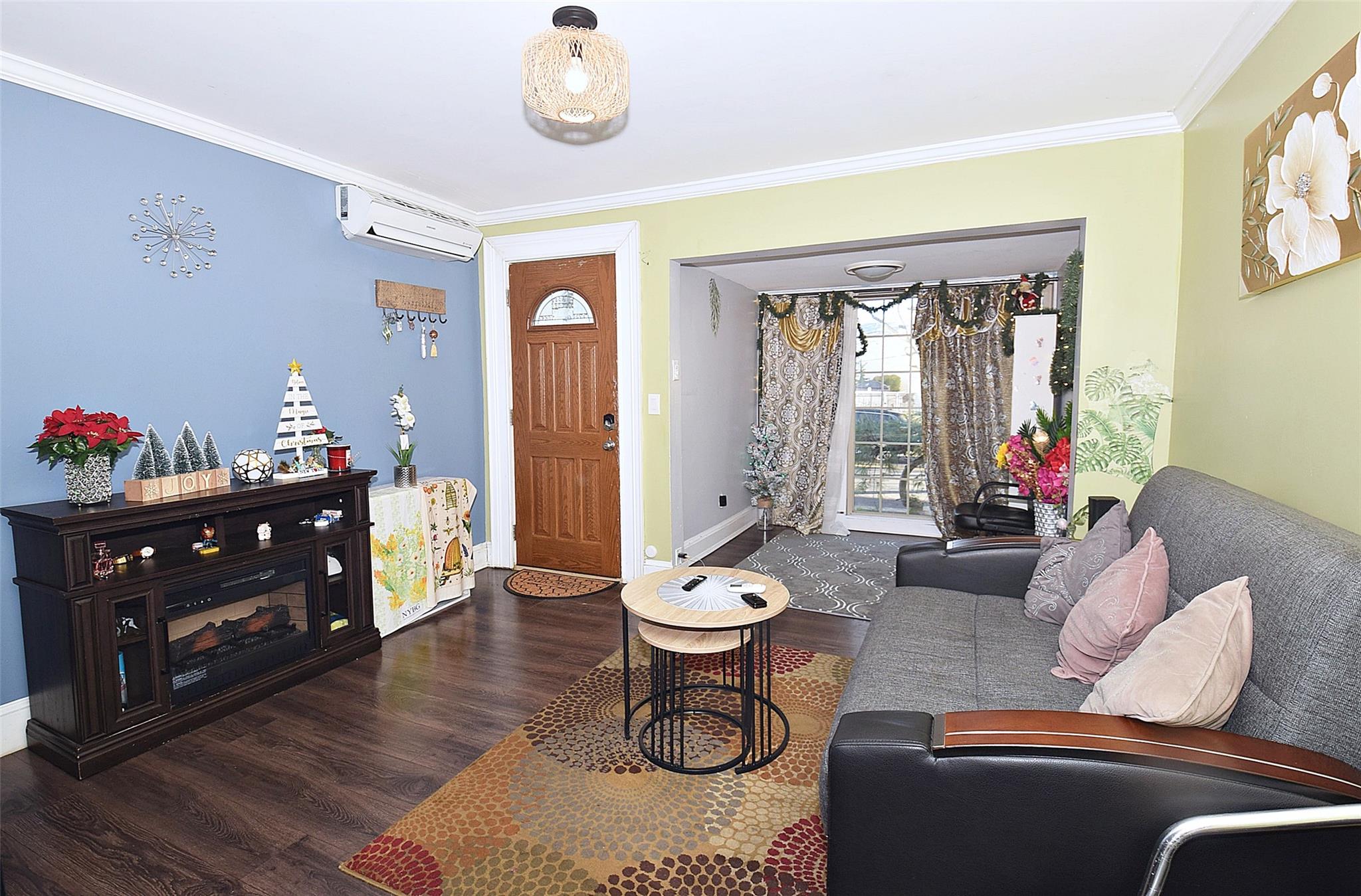 Living room with a wall mounted AC, dark hardwood / wood-style floors, and ornamental molding