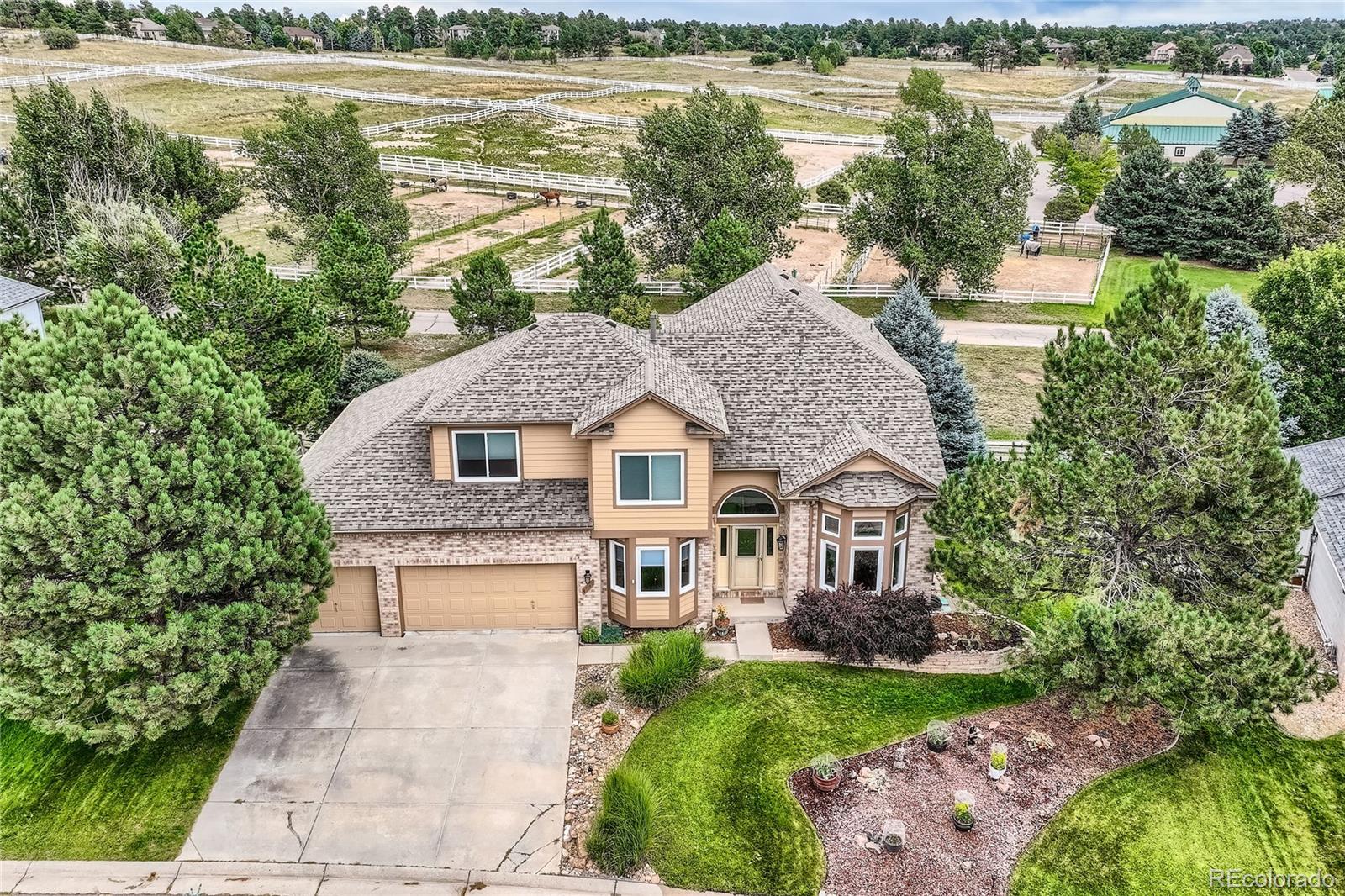 a aerial view of a house next to a lake with a large trees