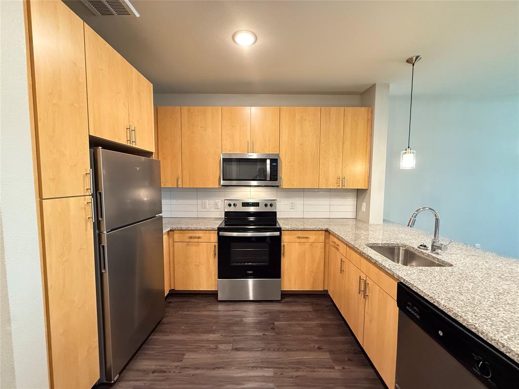 a kitchen with a sink a refrigerator a stove top oven and wooden floor