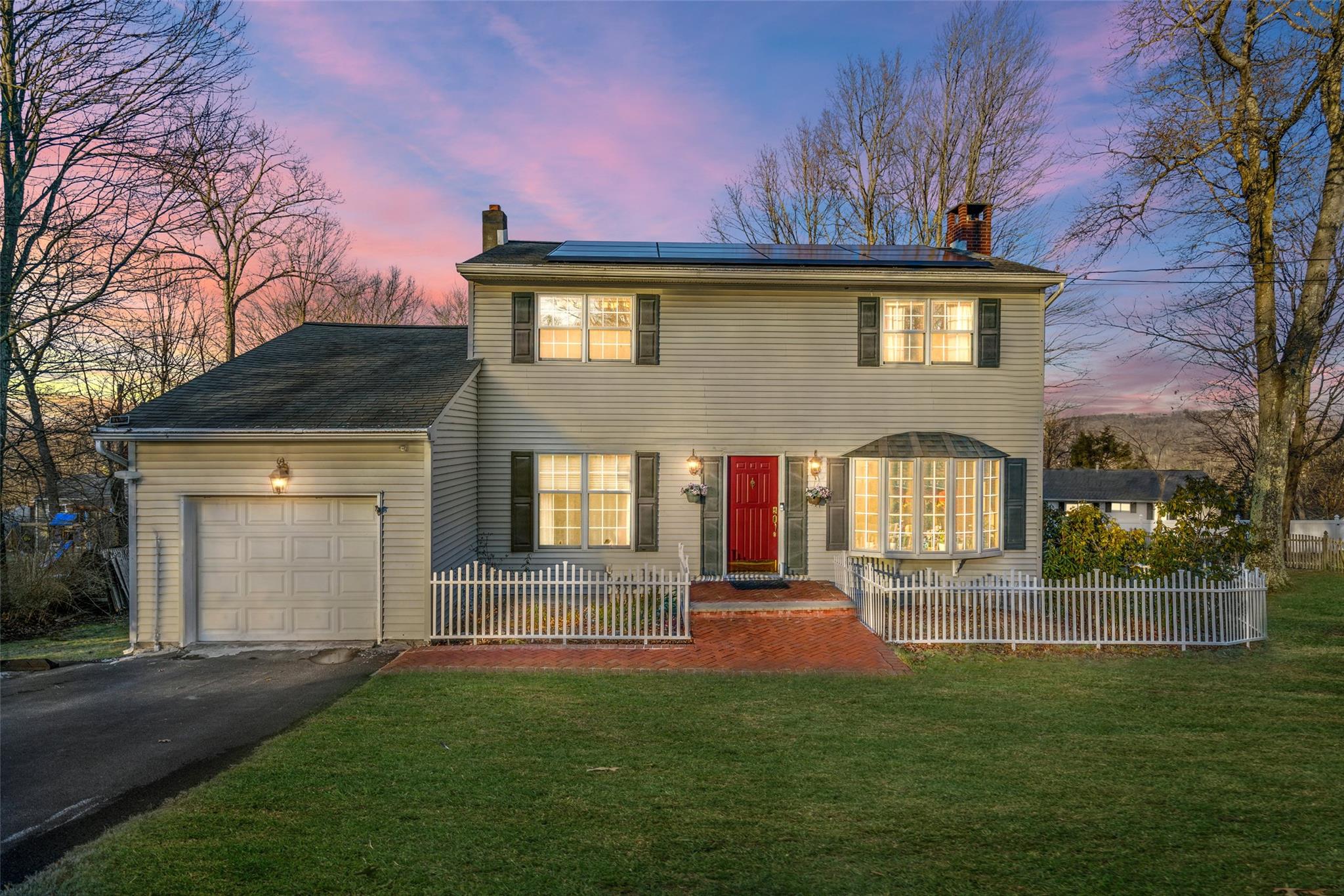 Colonial house featuring solar panels, a garage, and a yard