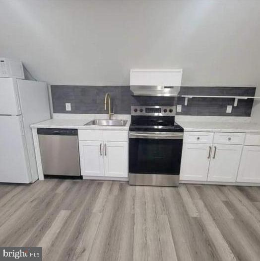 a kitchen with stainless steel appliances a stove a sink and white cabinets