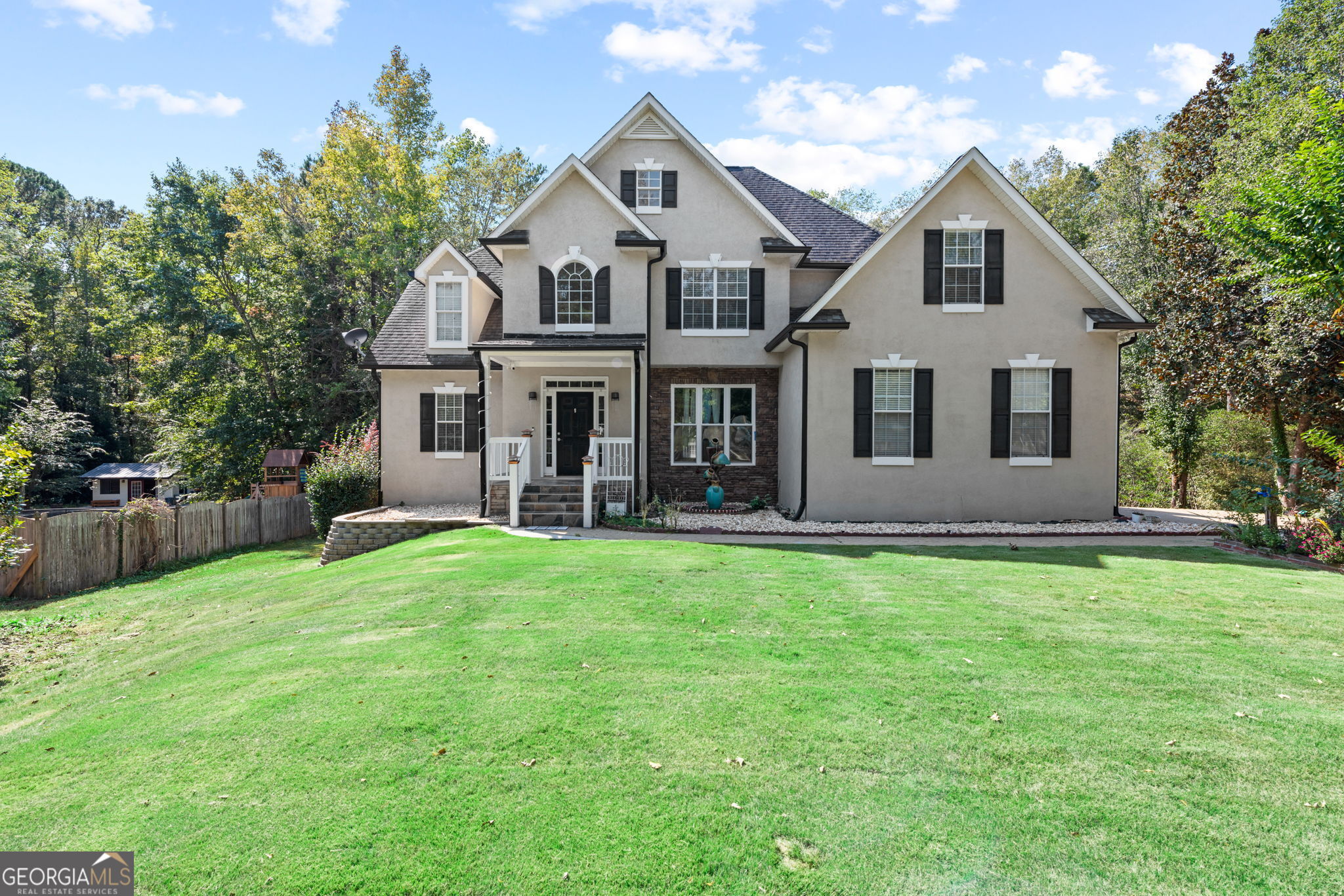 a front view of a house with a garden and trees