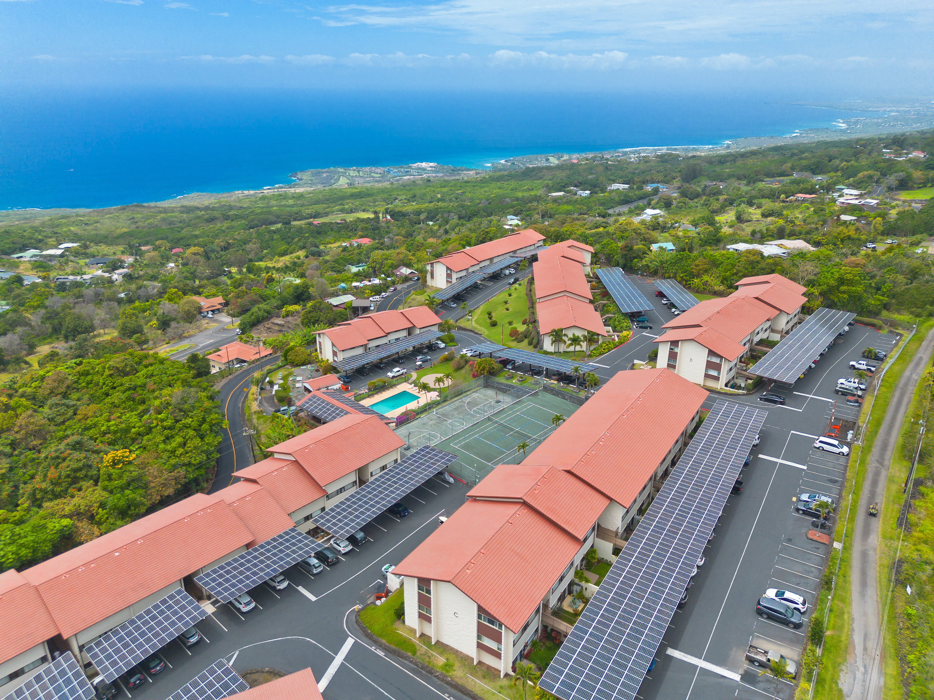 an aerial view of residential houses with outdoor space and ocean view