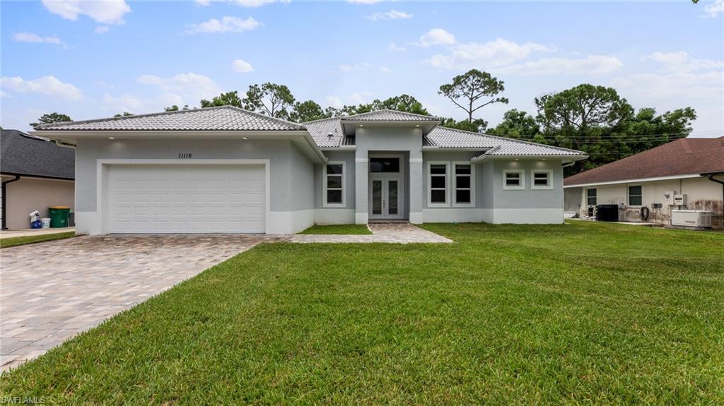 View of front of home with a garage, central AC, and a front lawn