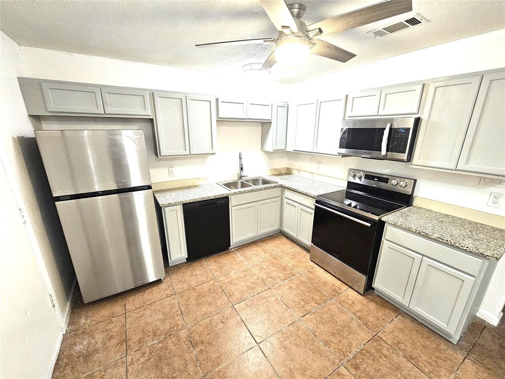 a kitchen with stainless steel appliances granite countertop a sink stove microwave and refrigerator