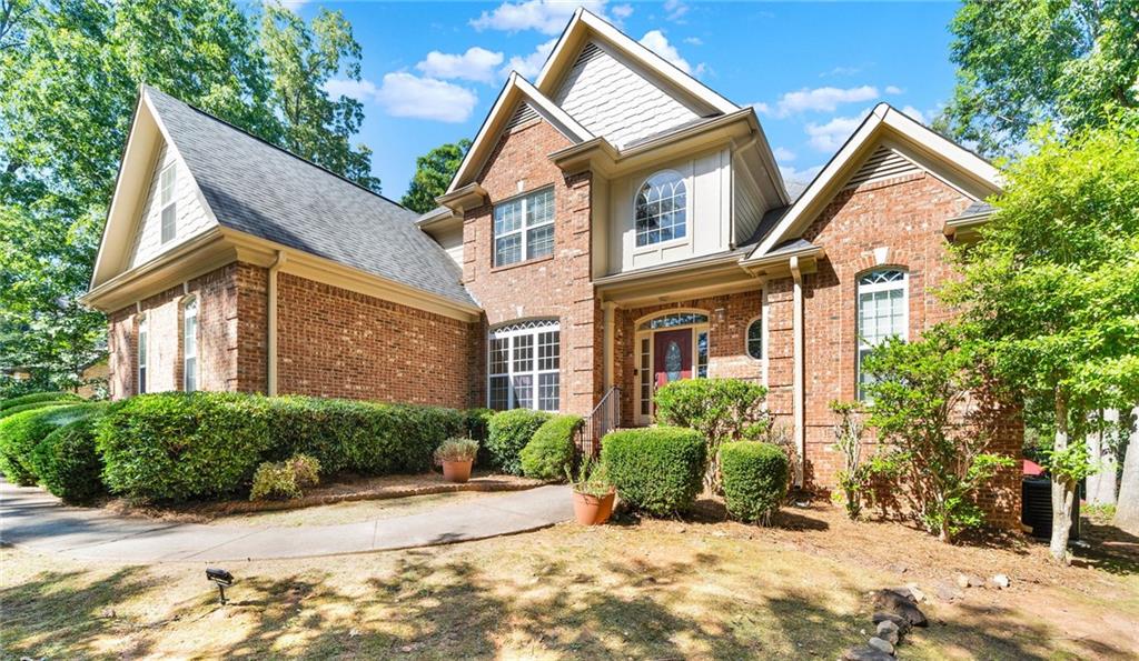 a view of a brick house with a yard and large trees