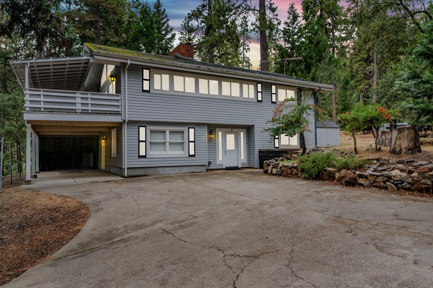 a front view of a house with a garden and trees