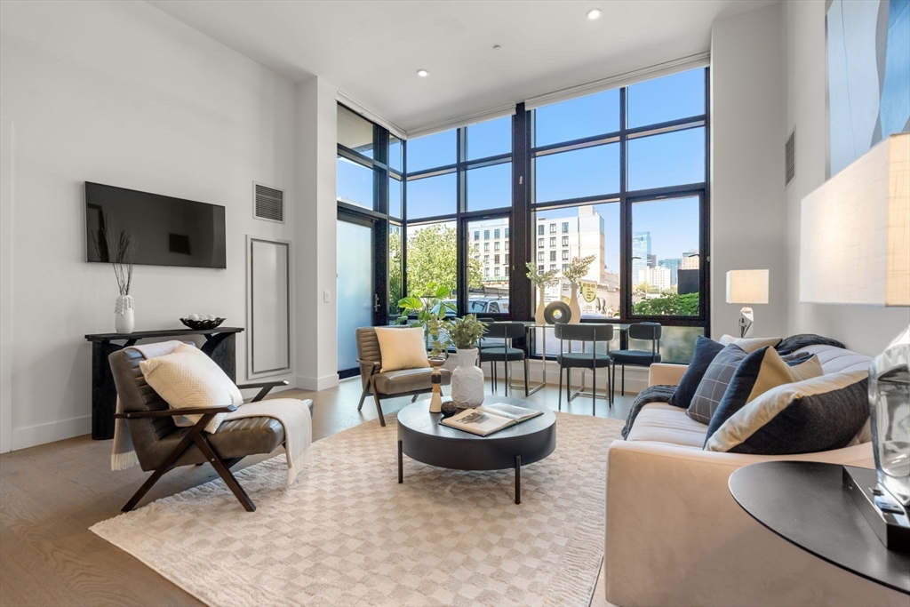 a living room with furniture a flat screen tv and a large window