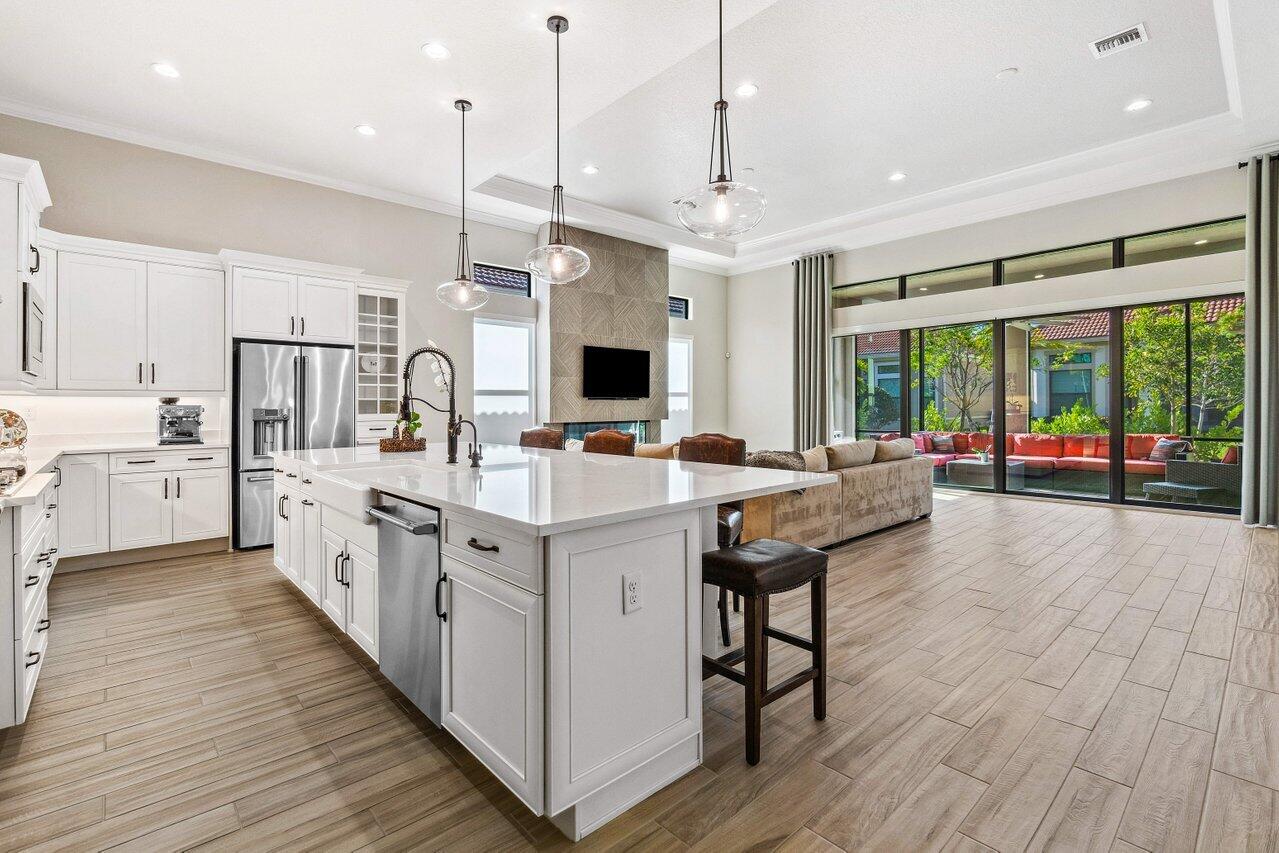 a large white kitchen with a large window a sink dishwasher and a stove with wooden floor