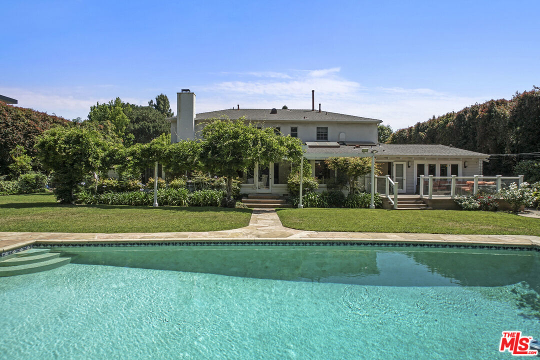 a view of a big house with a big yard and large trees