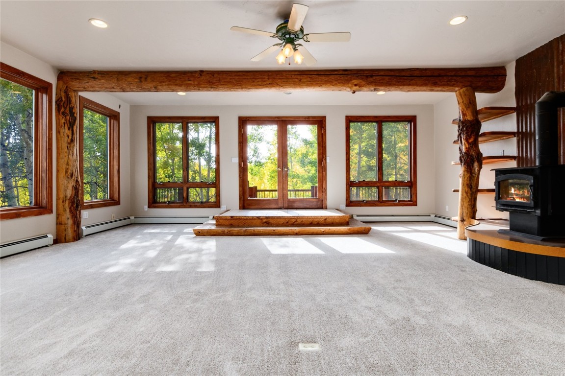 an empty room with large windows and a ceiling fan