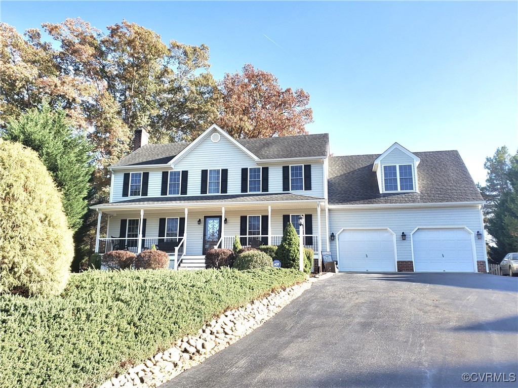 Colonial home featuring a garage and covered porch