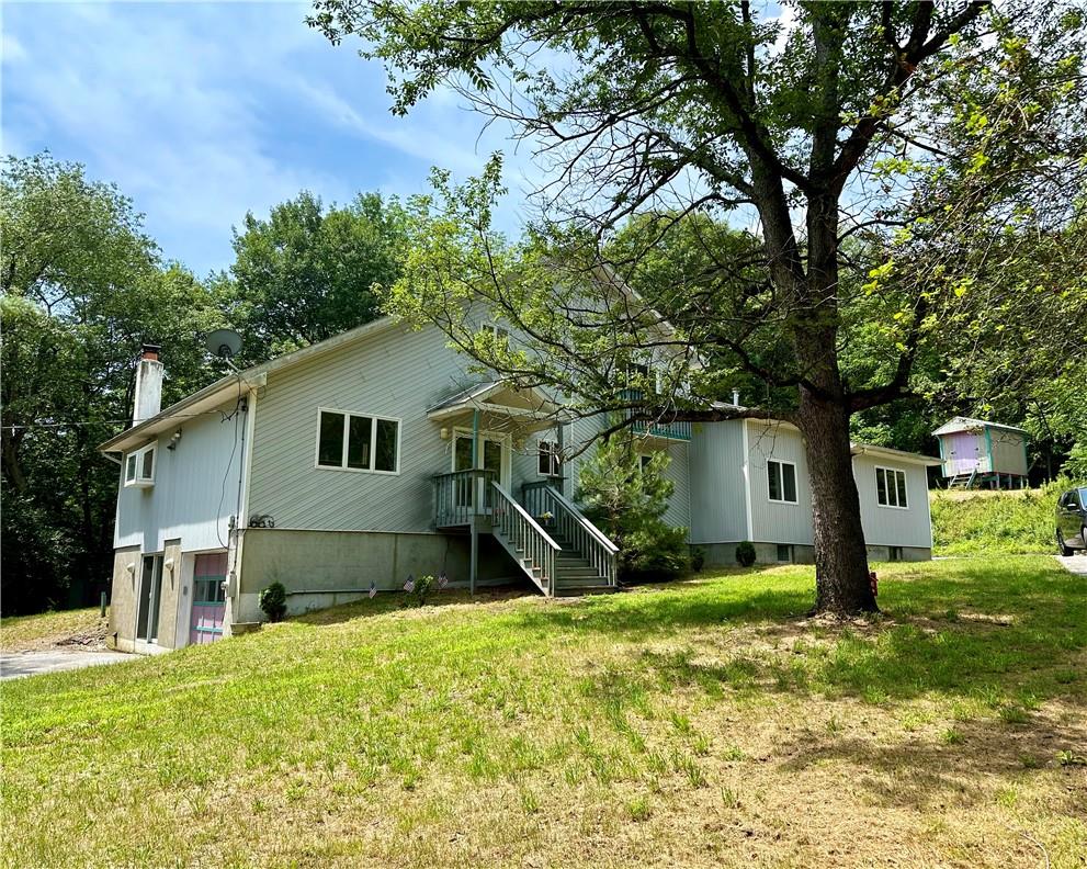 Back of property with a garage and a lawn