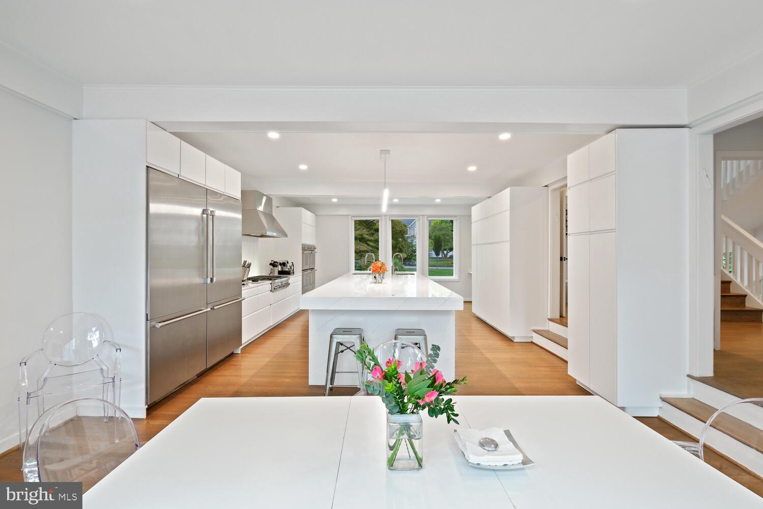 a large white kitchen with stainless steel appliances granite countertop a refrigerator and a sink