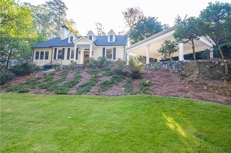 a view of a yard in front of a house with plants and large trees