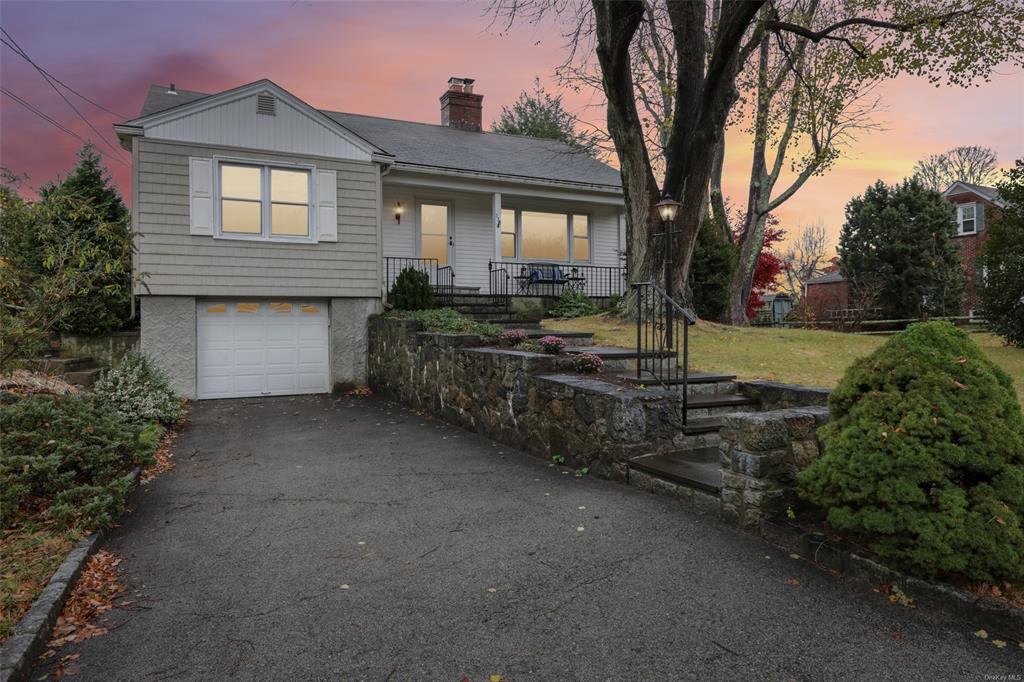 View of front of house featuring covered porch, a garage, and a lawn